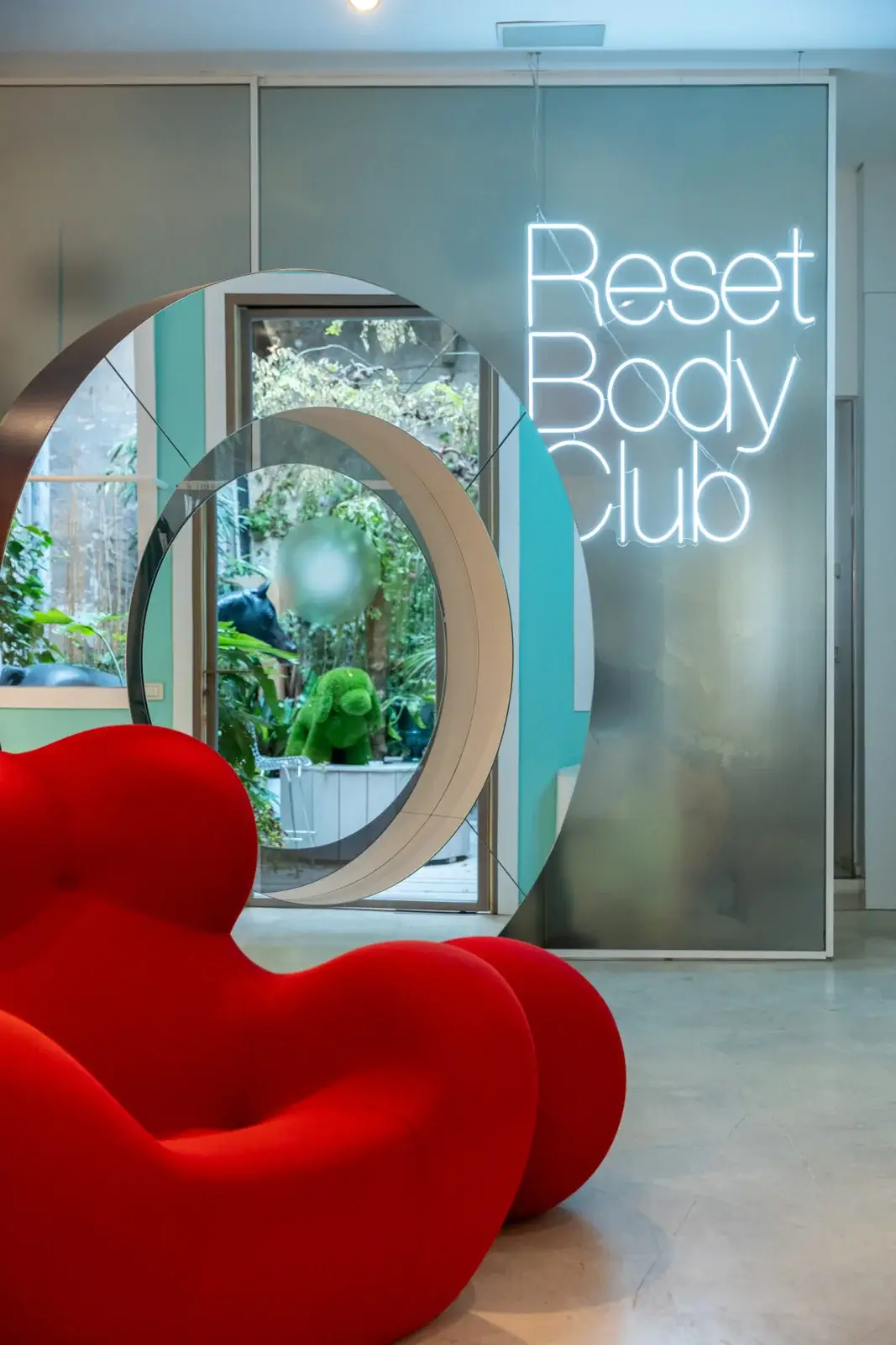 Spazio con specchi, neon e una poltrona rossa
